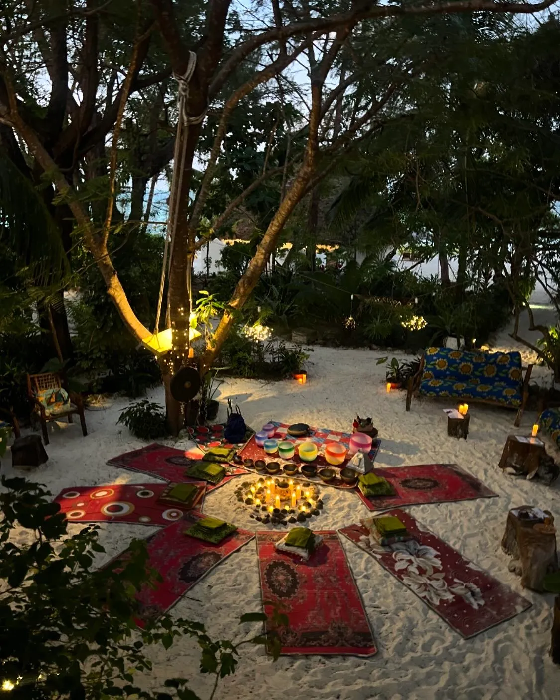 Altar ceremonial con velas y cuencos de sonido rodeado de tapetes al aire libre